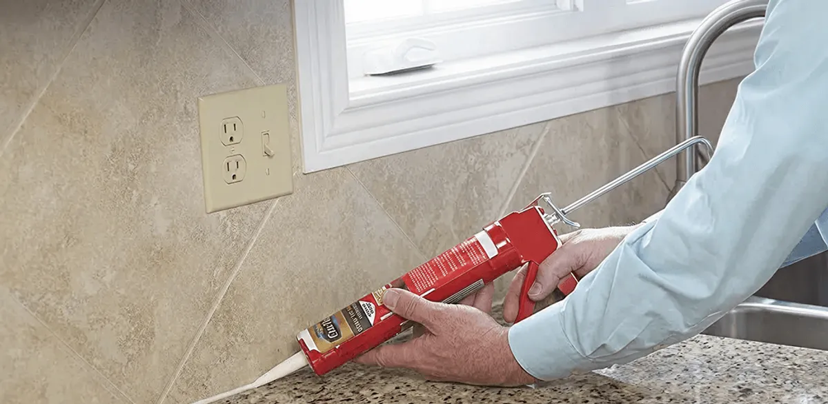 Handyman applying caulk along a kitchen backsplash and countertop seam in Boca Raton, FL