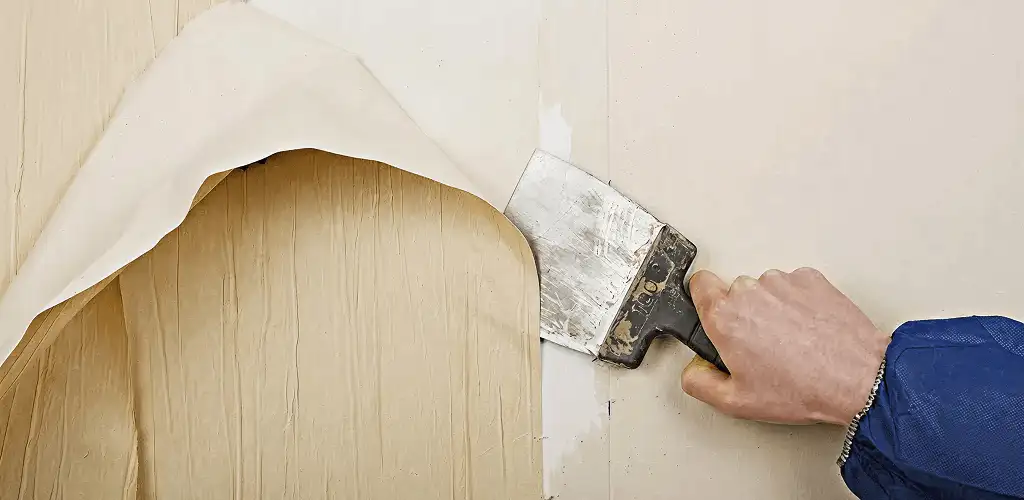 Handyman removing wallpaper with a scraper for wall preparation in Boca Raton, FL