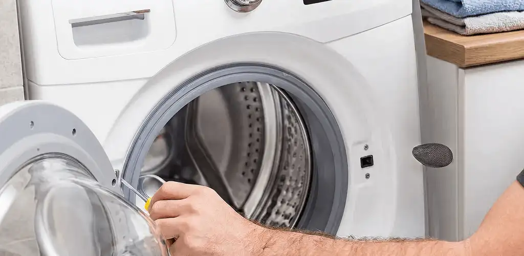 Handyman repairing a front-load washing machine and inspecting the drum in Boca Raton, FL